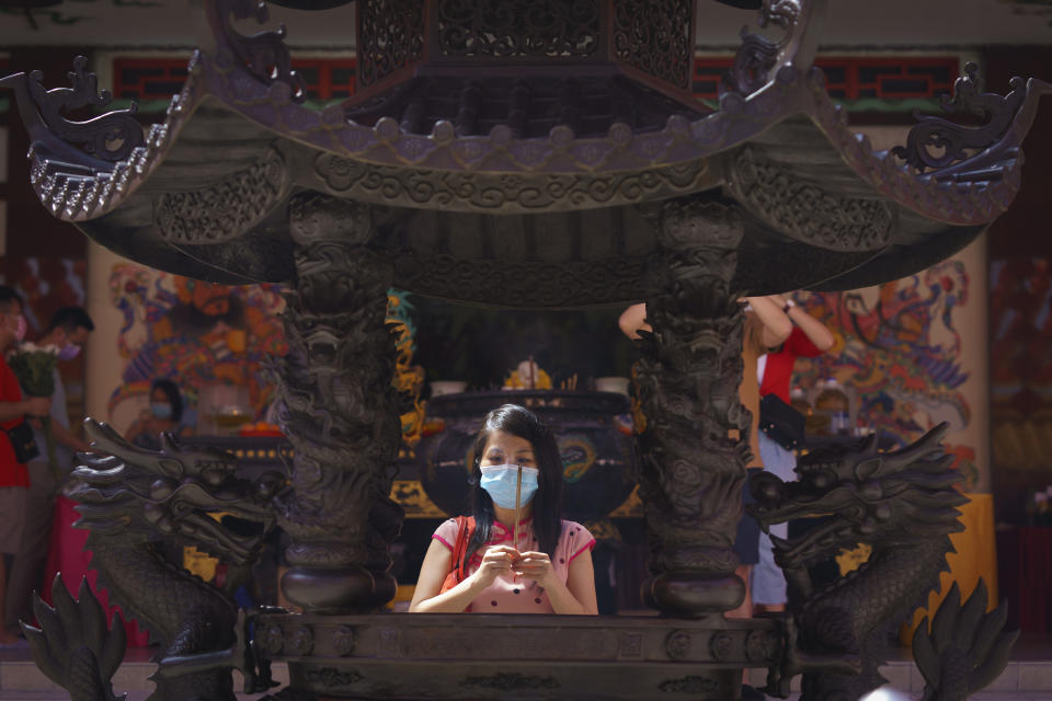 A woman wearing a protective mask prays at the Thean Hou Temple during first day of Chinese Lunar New Year celebrations in Kuala Lumpur, Friday, Feb. 12, 2021. The movement control order (MCO) currently enforced across the country to help curb the spread of the coronavirus, has been extended to Feb. 18, effectively covering the Chinese New Year festival that falls on Feb. 12 this year. (AP Photo/Vincent Thian)