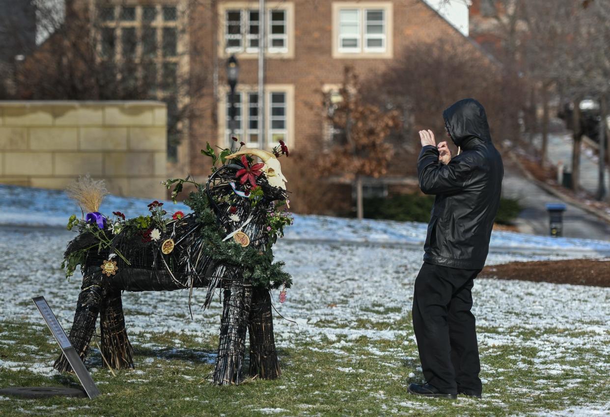 Nick Smith, of Lansing, takes a picture of the "yule goat" display seen on the Capitol lawn Tuesday, Dec. 19, 2023.