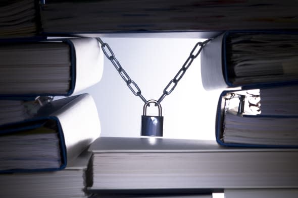 Stack of ringbinders holding up a padlock