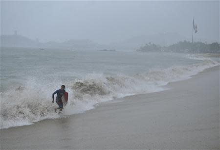 A surfer runs off a beach during rainfall brought on by Hurricane Raymond in Acapulco October 21, 2013. REUTERS/Jesus Solano