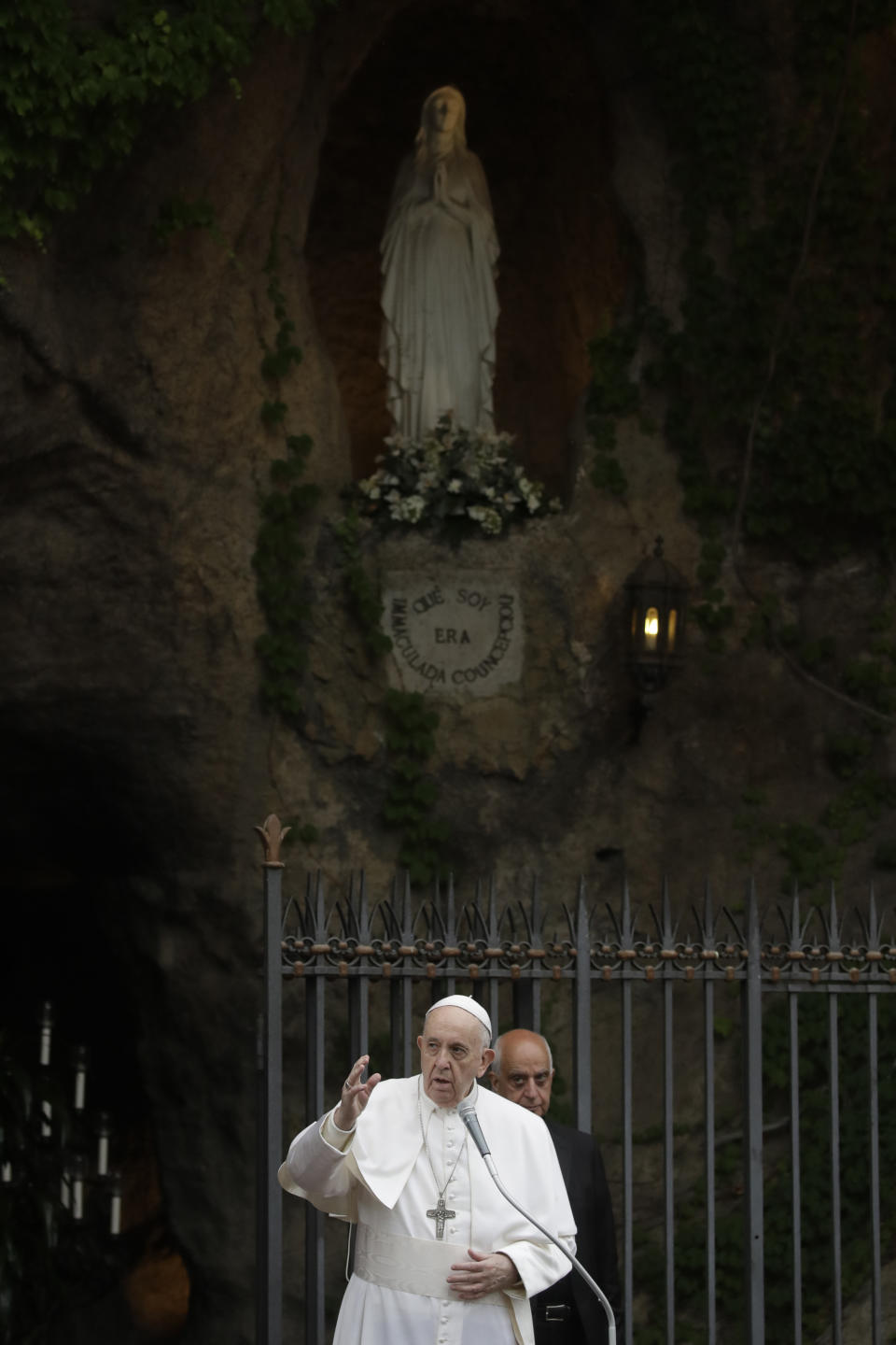 Pope Francis delivers his blessing at the end of a rosary in Vatican gardens Saturday May 30, 2020. In background is a reconstruction of the Lourdes' grotto in southern France, where the Virgin Mary is alleged to have appeared eighteen times to Bernadette Soubirous in 1858. Pope Francis is reciting a special prayer for the end of the coronavirus pandemic surrounded by a representative sampling of people on the front lines in his biggest post-lockdown gathering to date. (AP Photo/Alessandra Tarantino, pool)