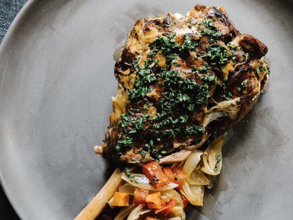 goat shoulder with greens on a grey plate