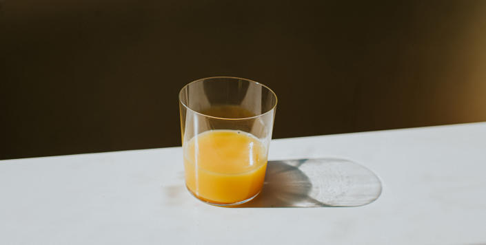 Single Glass of Orange Juice casting a shadow on a white surface with space for copy (Catherine Falls Commercial / Getty Images stock)