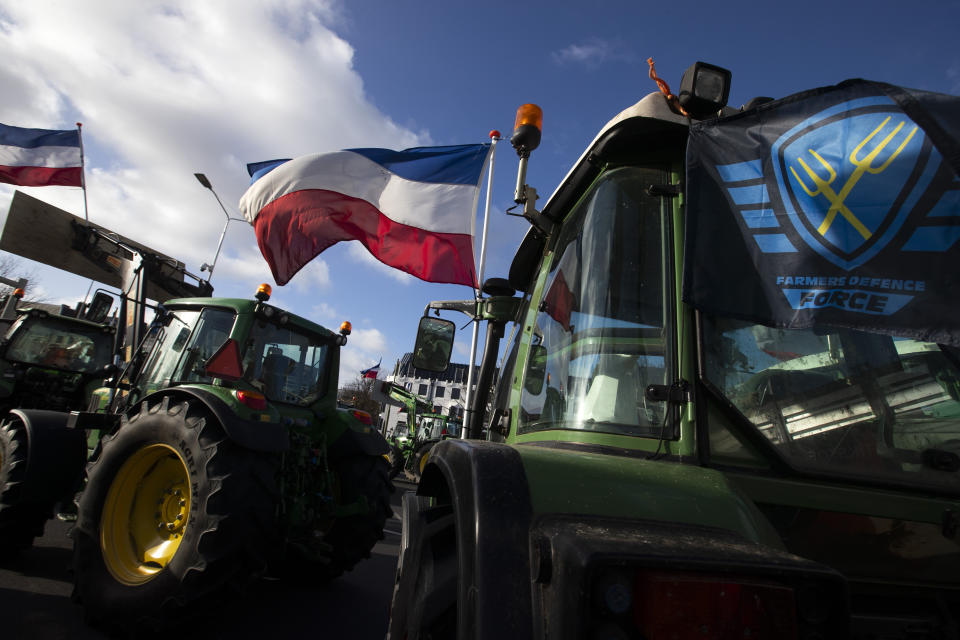 The Farmers Defense Force flag, right, and Dutch flags, fly in the wind on an intersection blocked by tractors in The Hague, Netherlands, Wednesday, Feb. 19, 2020. Dutch farmers, some driving tractors, poured into The Hague on Wednesday to protest government moves to rein in carbon and nitrogen emissions to better fight climate change. (AP Photo/Peter Dejong)