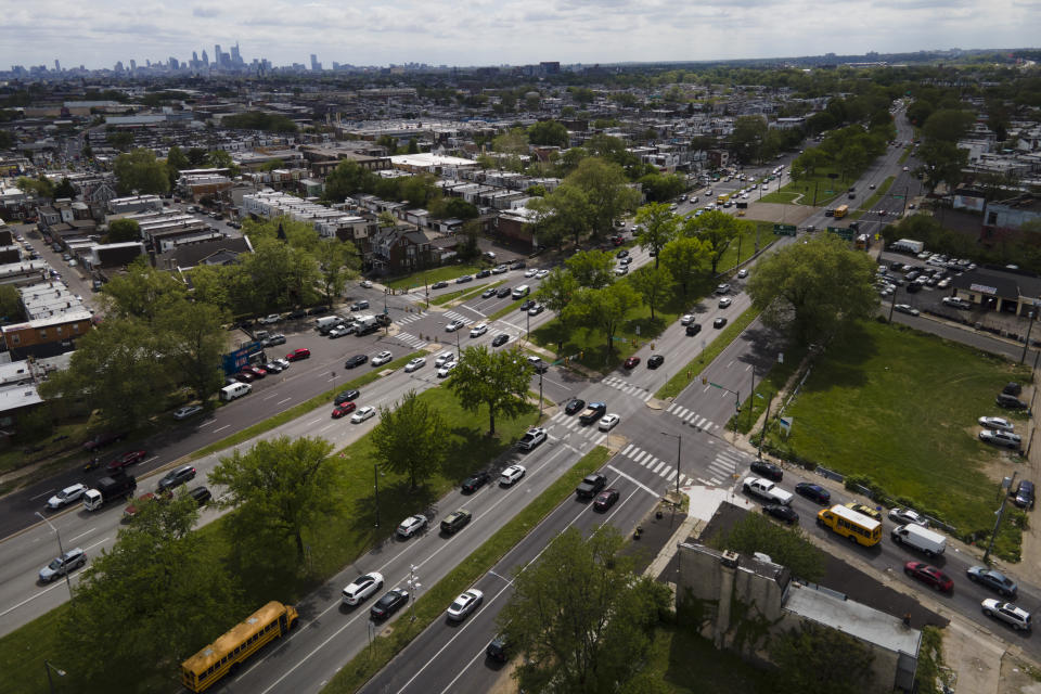 The Philadelphia skyline, top left, is seen at a distance as vehicular traffic flows along Roosevelt Boulevard at the intersection with North Mascher Ave, Thursday, May 12, 2022, in Philadelphia. Roosevelt Boulevard is an almost 14-mile maze of chaotic traffic patterns that passes through some of the city's most diverse neighborhoods and Census tracts with the highest poverty rates. Driving can be dangerous with cars traversing between inner and outer lanes, but biking or walking on the boulevard can be even worse with some pedestrian crossings longer than a football field and taking four light cycles to cross. (AP Photo/Julio Cortez)