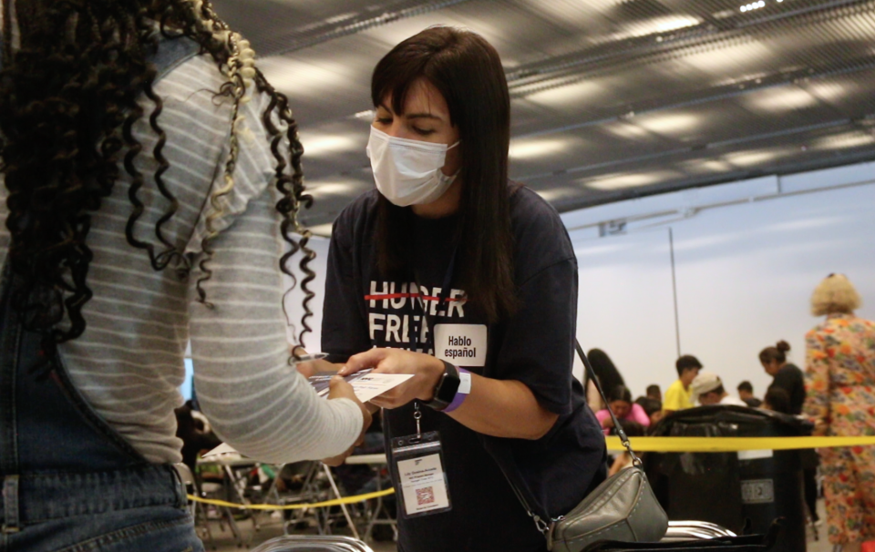 Lily Dosina, the WIC Program Manager at Hunger Free America, speaks with migrants at an August 2023 event in New York City. The organization works to connect migrants with food resources. / Credit: Aubrey Gelpieryn / CBS News