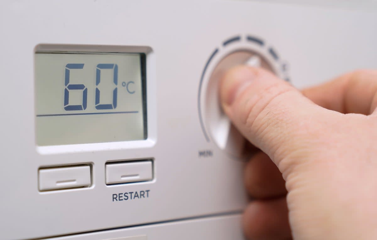 A homeowner turning down the temperature of a gas boiler (PA Wire)