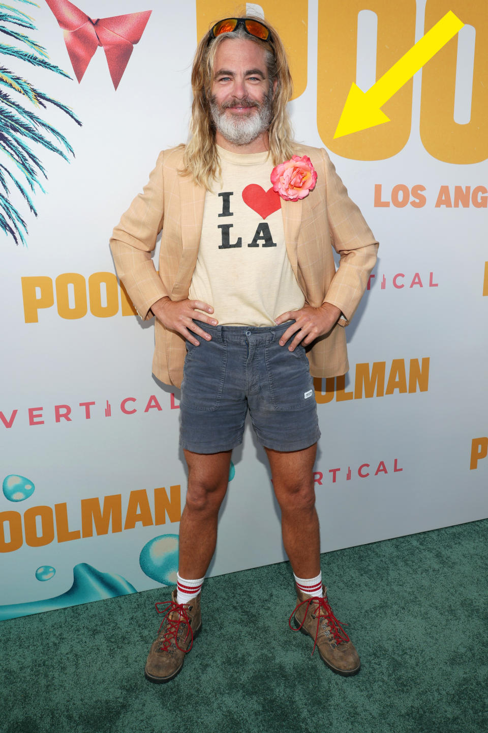 Chris Pine in beige jacket, "I ❤️ LA" shirt, denim shorts, with flower accessory at movie premiere