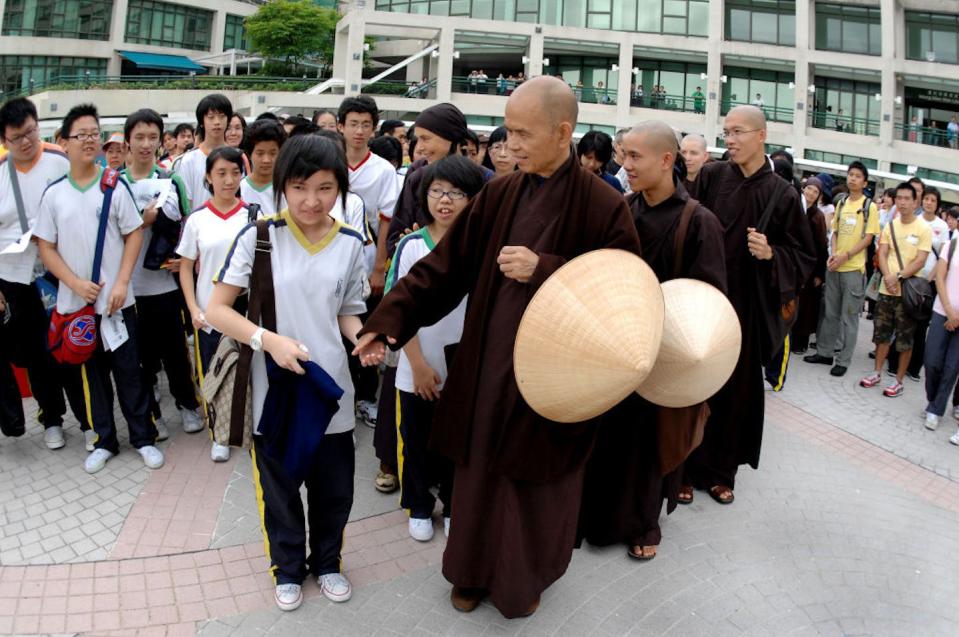 Zen master Thich Nhat Hanh reaches for a student’s hand during a meditation walk on a ‘day of mindfulness’ in Hong Kong in 2007. <a href="https://www.gettyimages.com/detail/news-photo/pupil-cheng-ka-ki-looks-surprised-as-zen-master-thich-nhat-news-photo/1125039441?phrase=thich%20nhat%20hanh&adppopup=true" rel="nofollow noopener" target="_blank" data-ylk="slk:Steve Cray/South China Morning Post via Getty Images;elm:context_link;itc:0;sec:content-canvas" class="link ">Steve Cray/South China Morning Post via Getty Images</a>