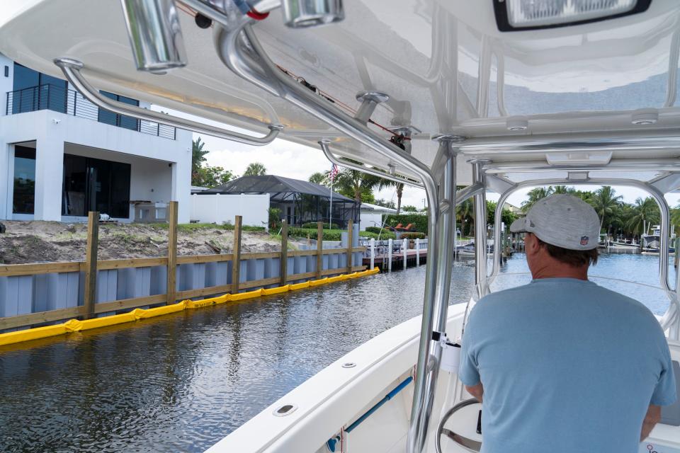 Mitch Huhn drives his boat past the home of a neighbor in Paradise Port who was cited for building a new bulkhead 7 to 9 feet waterward of the original bulkhead, in violation of the construction permit.