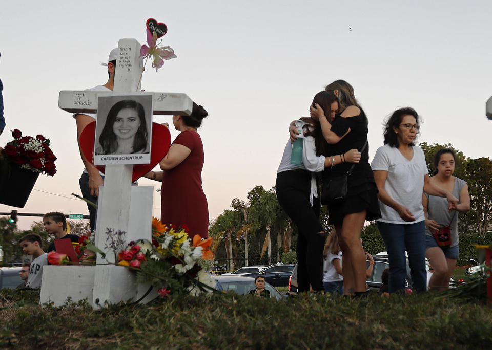 FILE - In this Feb. 18, 2018, file photo, Magaly Newcomb, right, comforts her daughter Haley Newcomb, 14, a student at Marjory Stoneman Douglas High School, at a memorial outside the school in Parkland, Fla. It’s been more than 1,000 days since a gunman with an AR-15 rifle burst into the school, killing 17 people and wounding 17 others. And yet, with Valentine’s Day on Sunday, Feb. 14, 2021, marking the three-year milestone, Nikolas Cruz’s death penalty trial is in limbo. (AP Photo/Gerald Herbert, File)