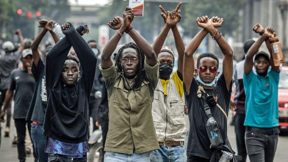 Protesters with their arms raised shout slogans at riot police during a protest against a proposed 2024 financial law, in Nairobi, Kenya, June 18, 2024