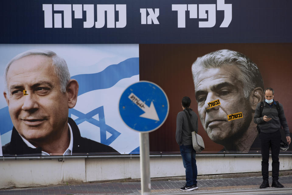 FILE - In this March 14, 2021, file photo, people stand in front of an election campaign billboard for the Likud party showing a portrait of its leader Prime Minister Benjamin Netanyahu, left, and opposition party leader Yair Lapid, in Ramat Gan, Israel. Netanyahu's political career seemed all but over, but now, as Israel and Gaza’s Hamas rulers wage war, Netanyahu’s fortunes have changed dramatically. His rivals’ prospects have crumbled, Netanyahu is back in his comfortable role as Mr. Security, and the country could soon be headed for yet another election campaign. (AP Photo/Oded Balilty, File)