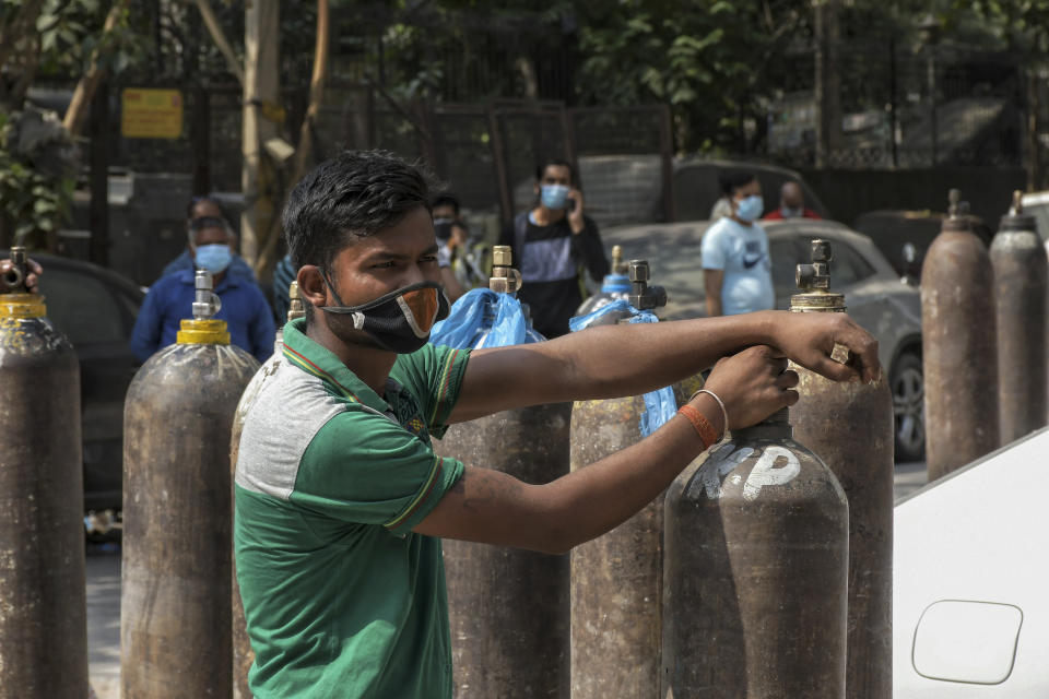 Family members of COVID-19 patients wait in queue to refill their oxygen cylinders at Mayapuri area in New Delhi, India, Monday, May 3, 2021. Indian hospitals are struggling to secure a steady supply of oxygen, and more COVID-19 patients are dying amid the shortages. (AP Photo/ Ishant Chauhan)