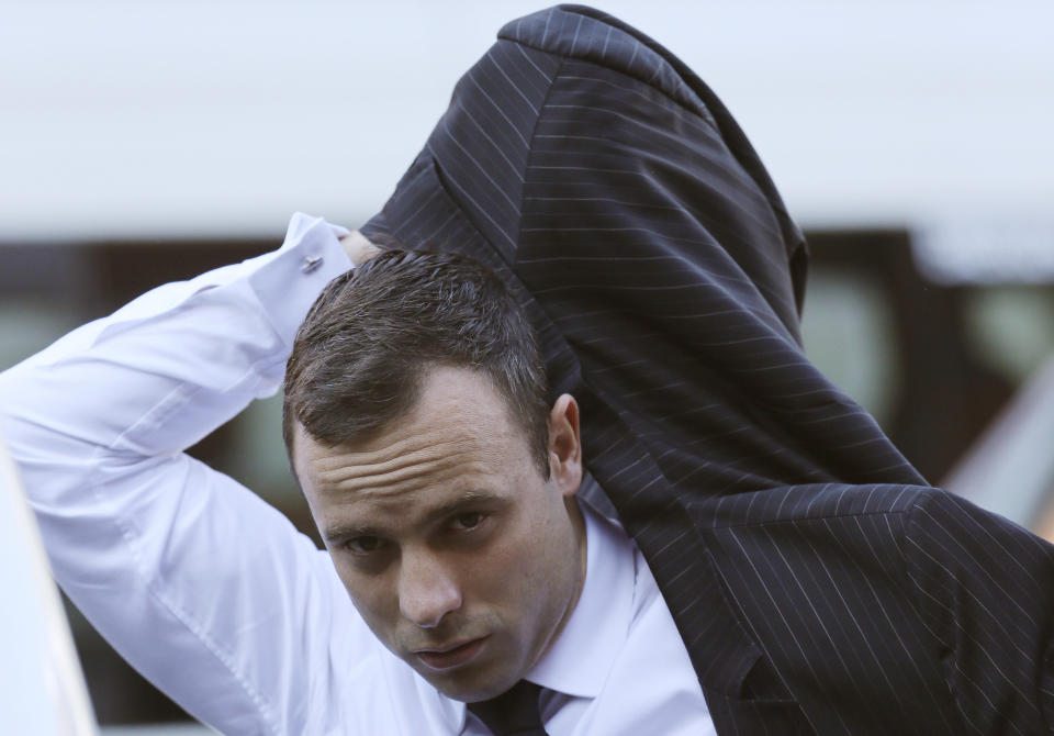 Oscar Pistorius puts on his jacket as he arrives at the high court in Pretoria, South Africa, Friday, April 11, 2014. The chief prosecutor laughed scornfully at an answer from Pistorius during the Olympic athlete's murder trial Thursday, mocking the man who shot his girlfriend. Pistorius is charged with murder for the shooting death of his girlfriend, Reeva Steenkamp, on Valentines Day in 2013. (AP Photo/Themba Hadebe)