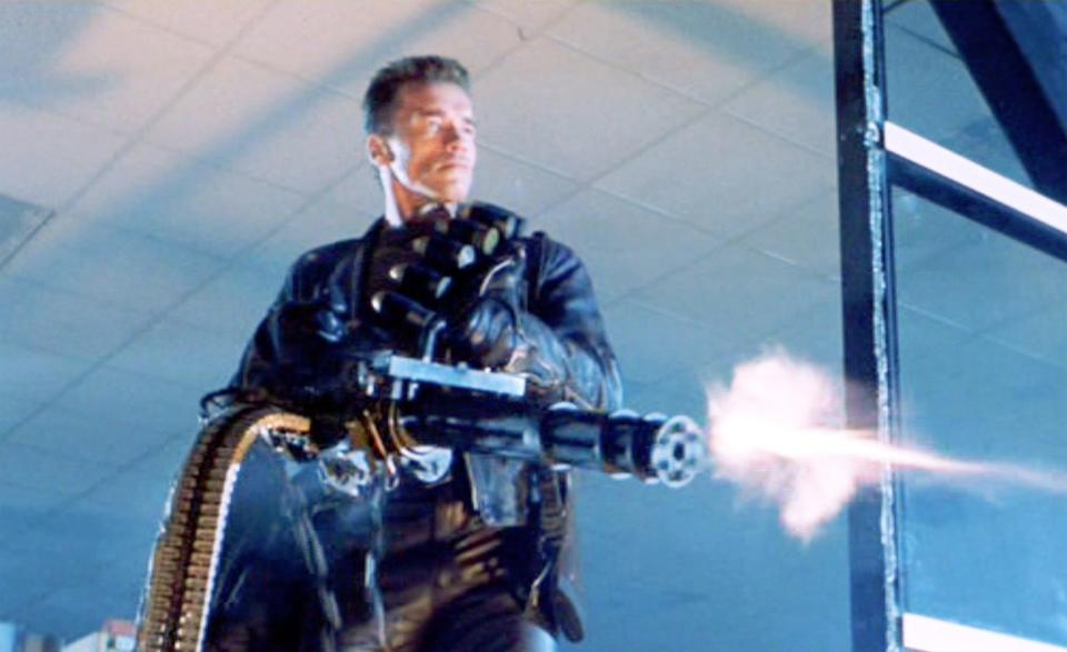The movie "Terminator 2: Judgment Day", (alt: T2) directed by James Cameron. Seen here, Arnold Schwarzenegger (as the T-800 Terminator). He fires a handheld minigun (machine gun).
