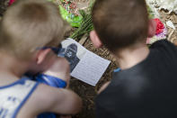 <p>Children read a sympathy card left at the feet of a gorilla statue at the Cincinnati Zoo & Botanical Garden. <em>(AP Photo/John Minchillo)</em> </p>