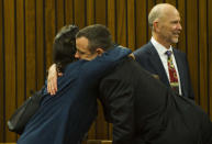 Oscar Pistorius, center, gets a hug from a relative, left, with uncle Arnold Pistorius, right, in court in Pretoria, South Africa, Thursday, April 17, 2014. Pistorius is charged with the murder of his girlfriend, Reeva Steenkamp, on Valentines Day in 2013. (AP Photo/Alet Pretorius, Pool)