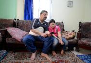 Syrian refugee Fares al-Bashawat sits with his 10-year-old son Nemr at a house in the Egyptian port city of Alexandria on April 23, 2015