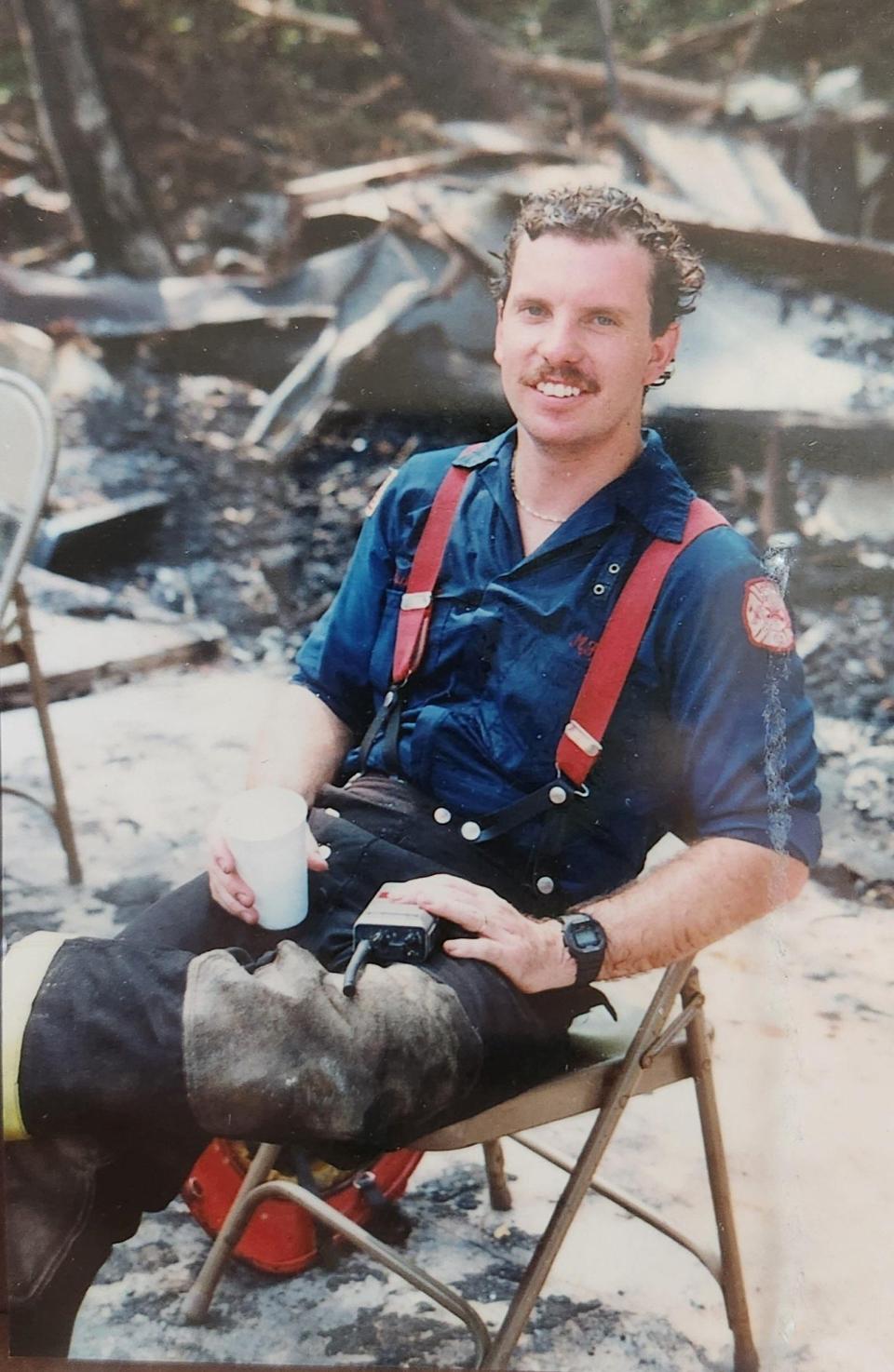 Danny Kuhlmann sits amidst rubble in his Columbia County Fire uniform.
