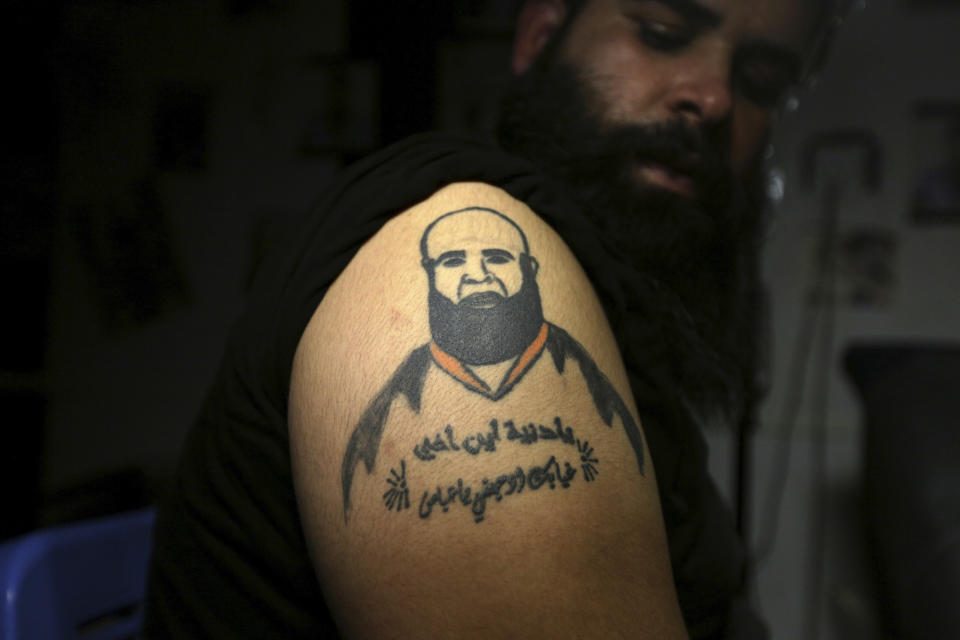 In this Tuesday. Oct. 23, 2018, photo, Zuhair Atwan displays tattoo of his brother, who was killed in sectarian violence, in a tattoo studio in Baghdad, Iraq. The Arabic sentence on his arm reads, "Oh life, where is my brother? Your absence hurts me, oh Abbas." (AP Photo/Hadi Mizban)