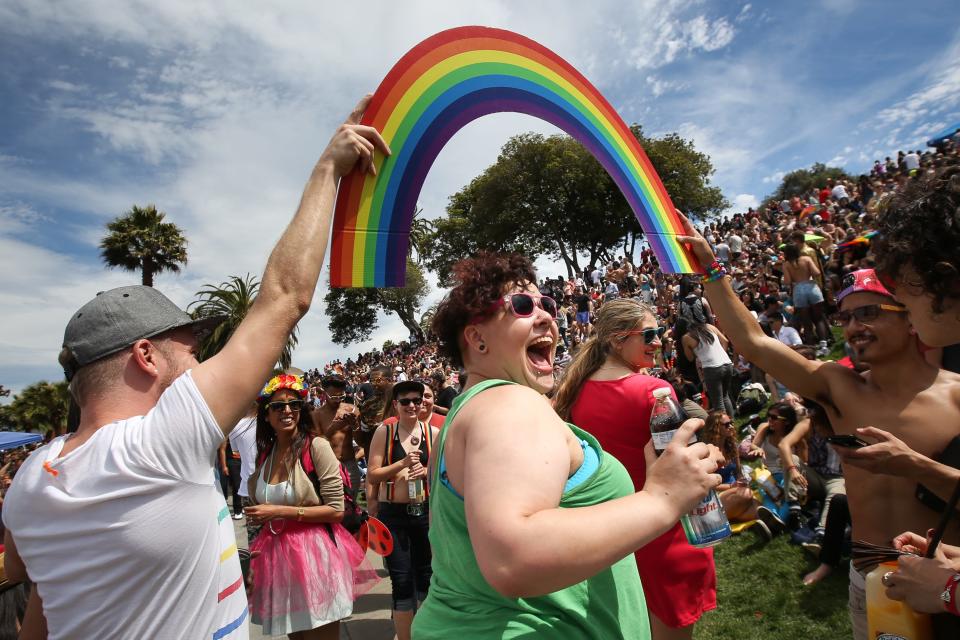 Daniela Lopez smiles as she walks under a rainbow held by two men during a gay pride celebration in Dolores Park on June 27, 2015 in San Francisco, Calif.