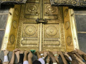 Muslim pilgrims touch the golden door of the Kaaba, the cubic building at the Grand Mosque, as they pray ahead of the annual Hajj pilgrimage in the Muslim holy city of Mecca, Saudi Arabia, Friday, Aug. 17, 2018. The annual Islamic pilgrimage draws millions of visitors each year, making it the largest yearly gathering of people in the world. (AP Photo/Dar Yasin)