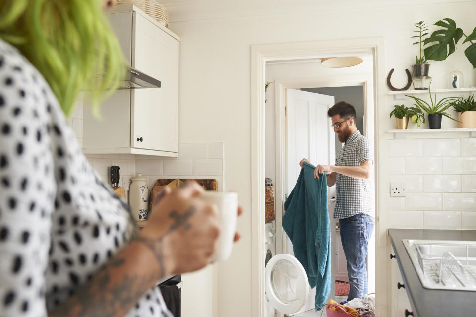 Husband doing laundry while wife watches