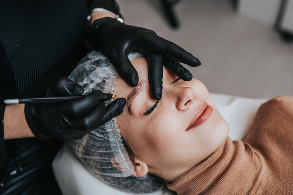 woman in chair getting microblading done