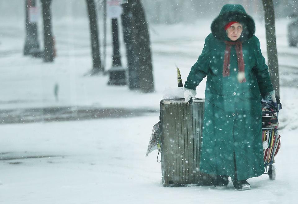 A woman struggles with bags as she walks through the empty streets of Boston as the snow begins to fall from a massive winter storm on January 4, 2018 in Boston, Massachusetts.