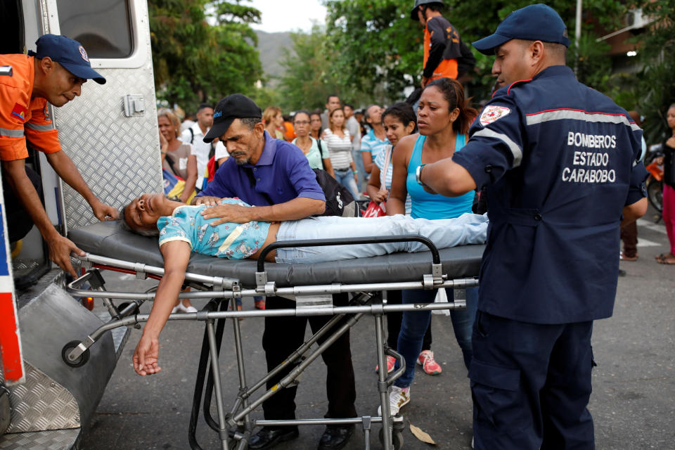 Paramedics help a woman who fainted outside the lockup where a fire occurred in Valencia, Venezuela on March 28, 2018.