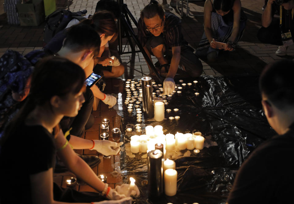 People light candles during a vigil to mourn the recent suicide of a woman due to the government's policy on the extradition bill, in Hong Kong Saturday, July 6, 2019. A vigil is being held in Hong Kong for a woman who fell to her death this week, one of three apparent suicides linked to ongoing protests over fears that freedoms are being eroded in this semi-autonomous Chinese territory. (AP Photo/Vincent Yu)