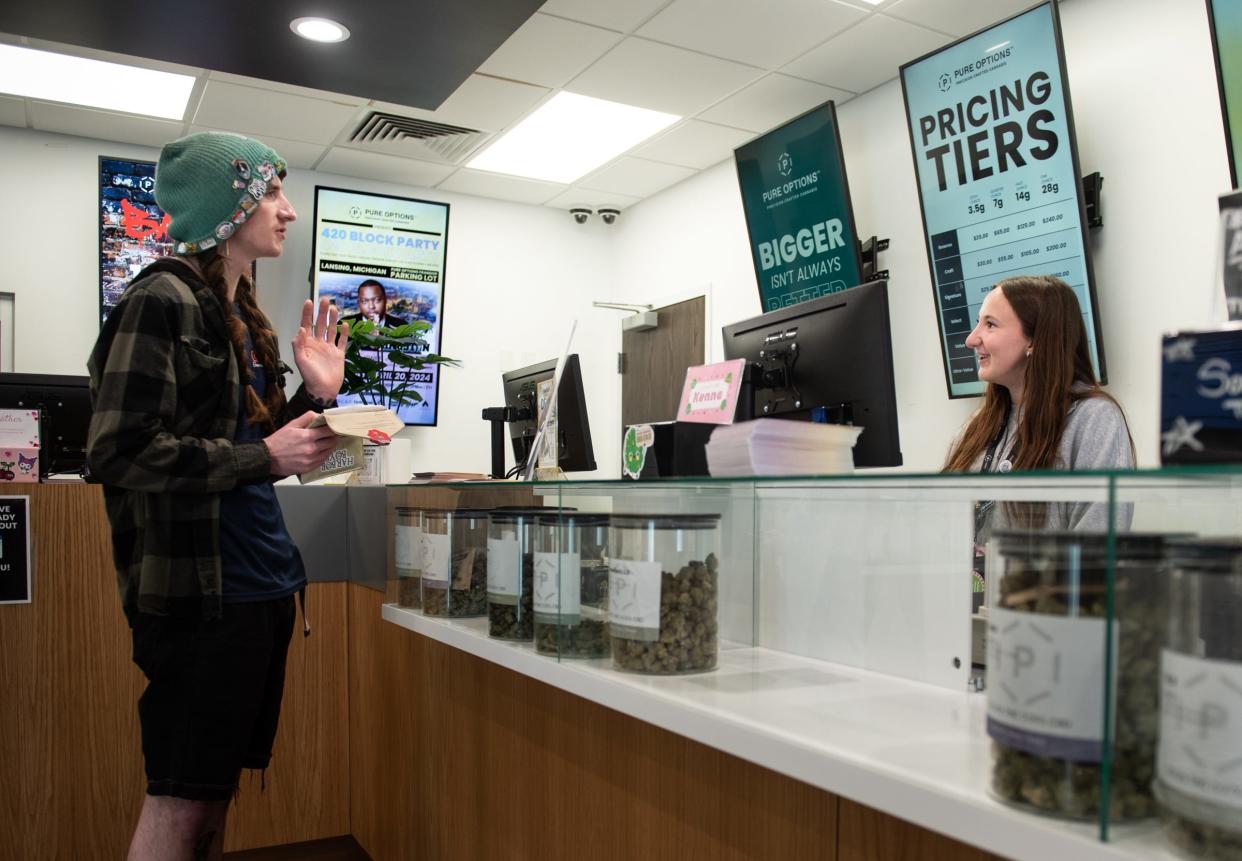 Brett Geiger of Webberville, left, chats with Pure Options budtender Kenna Preadmore, Wednesday, April 17, 2024, at Pure Options' Frandor location. The store is hosting a '420 Block Party' with live music and sales on merchandise through April 20th.