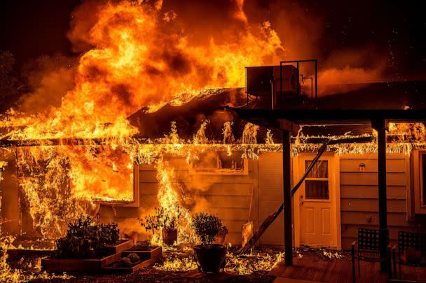 PHOTO: Flames consume a home on Triangle Rd. as the Oak Fire burns in Mariposa County, Calif., July 23, 2022. (Noah Berger/AP)