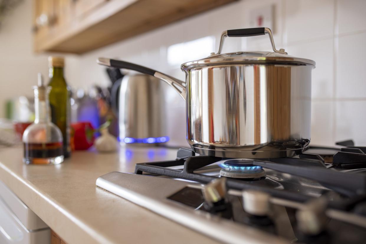 Close-up side-view shot of a cooking pot on a gas stove. Using a single ring to save extra cost of using gas as current energy prices increase.