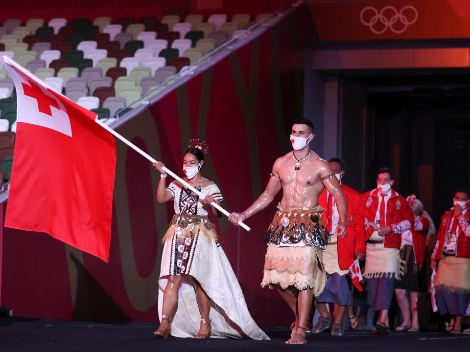 Pita Taufatofua, pictured on the right leading the Tongan team out during the Opening Ceremony of the Tokyo 2020 Olympic Games, has been unable to contact his loved ones since the natural disaster. (Getty Images)