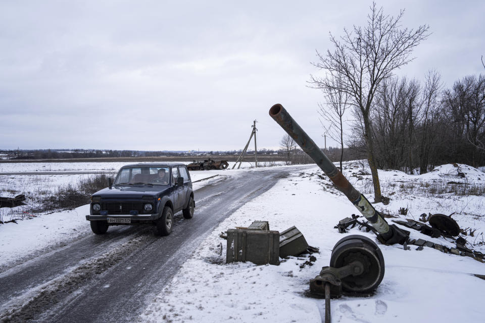 A car drives past a destroyed tank at the former positions of Russian forces in Ridkodub village, Ukraine, Wednesday, Feb. 15, 2023. (AP Photo/Evgeniy Maloletka)