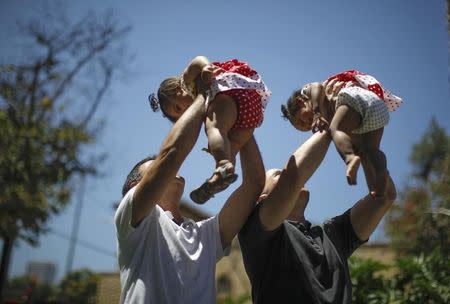 Jason Howe, 48, and Adrian Perez (L), 48, who were married in Spain, and again in California, hold their one-year-old twin daughters Clara (R) and Olivia at a playground in West Hollywood, California after the United States Supreme court ruled on California's Proposition 8 and the federal Defense of Marriage Act, June 26, 2013. REUTERS/Lucy Nicholson