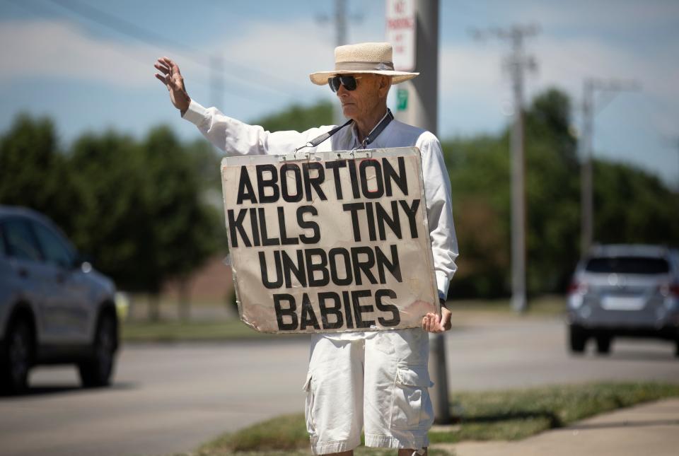 Standing in front of the Women's Med Center in Kettering, near Dayton, Ohio, Dave Herbert, 84, of Centerville, waves as people honk their support, Friday, June 24, 2022. A few yelled profanity. Herbert has been fighting abortion at this spot for 15-20 years. On the overturn of Roe vs. Wade, he said, "Now I hope states ban abortion at any stage."