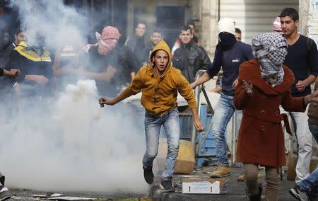 A Palestinian protester returns back a tear gas canister fired by Israeli troops following a protest demanding Israel to return the bodies of Palestinians who allegedly stabbed Israelis, in the West Bank city of Hebron November 4, 2015. REUTERS/Mussa Qawasma