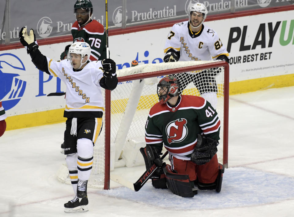 Pittsburgh Penguins right wing Bryan Rust (17) celebrates his goal with center Sidney Crosby (87) as New Jersey Devils goaltender Scott Wedgewood (41) reacts during the second period of an NHL hockey game Saturday, March 20, 2021, in Newark, N.J. (AP Photo/Bill Kostroun)