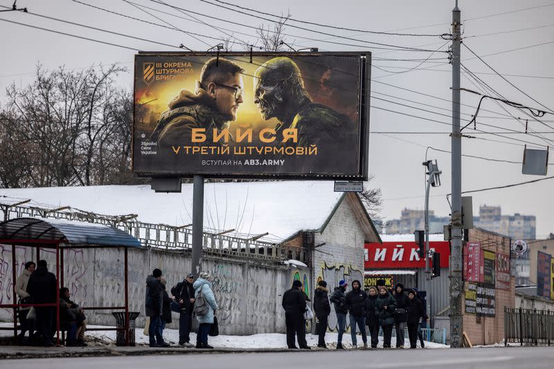 FILE PHOTO: People walk past a poster advertising the 3rd Separate Assault Brigade of the Ukrainian Ground Forces in Kyiv