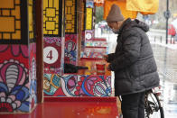 A man wearing a face mask to help protect against COVID-19 prepares to eat noodles on the street of Wuhan in central China's Hubei Province, Sunday, Jan. 23, 2022. Sunday will mark two years since the city of Wuhan was placed under a 76-day lockdown as China tried to contain the first major outbreak of the coronavirus pandemic. (AP Photo)