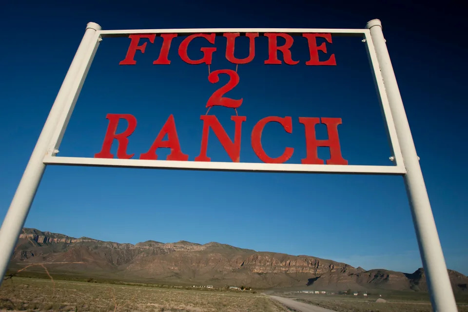 A sign reads "Figure 2 Ranch" in red letters with arid, brown hills in the background.