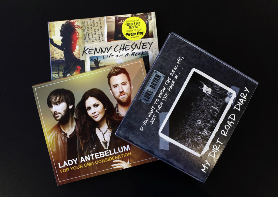 This Oct. 30, 2013 photo shows CDs of Luke Bryan, Lady Antebellum and Kenny Chesney that were produced to influence voters of the CMA Awards in Nashville, Tenn. The CMA encourages artists and their labels to educate voters, allowing three email blasts and one mailed product a year. (AP Photo/Mark Humphrey)