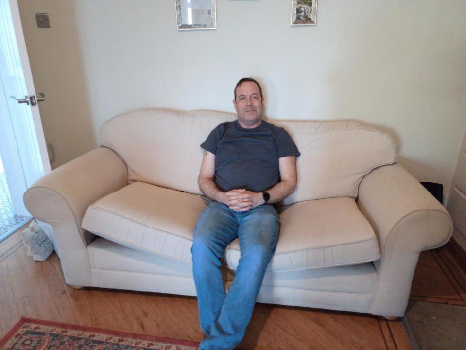 York Press: Darren Leeming, 54, sits on a couch he got for free from Facebook Marketplace. Picture: SWNS