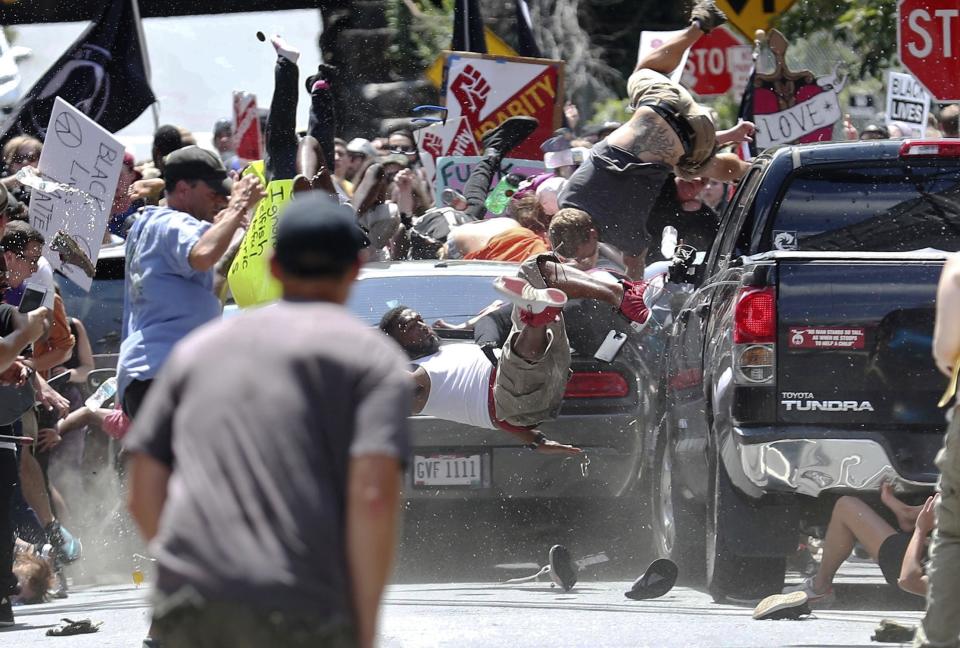 FILE - In this Aug. 12, 2017, file photo, people fly into the air as a vehicle drives into a group of protesters demonstrating against a white nationalist rally in Charlottesville, Va. Efforts to take down America’s monuments honoring slain Confederate soldiers and the generals who led them gained explosive momentum following the deadly violence a year ago in Charlottesville. The vehicle plowed into a crowd protesting a gathering of white supremacists whose stated goal was to protect a statue of Gen. Robert E. Lee. (Ryan M. Kelly/The Daily Progress via AP, File)