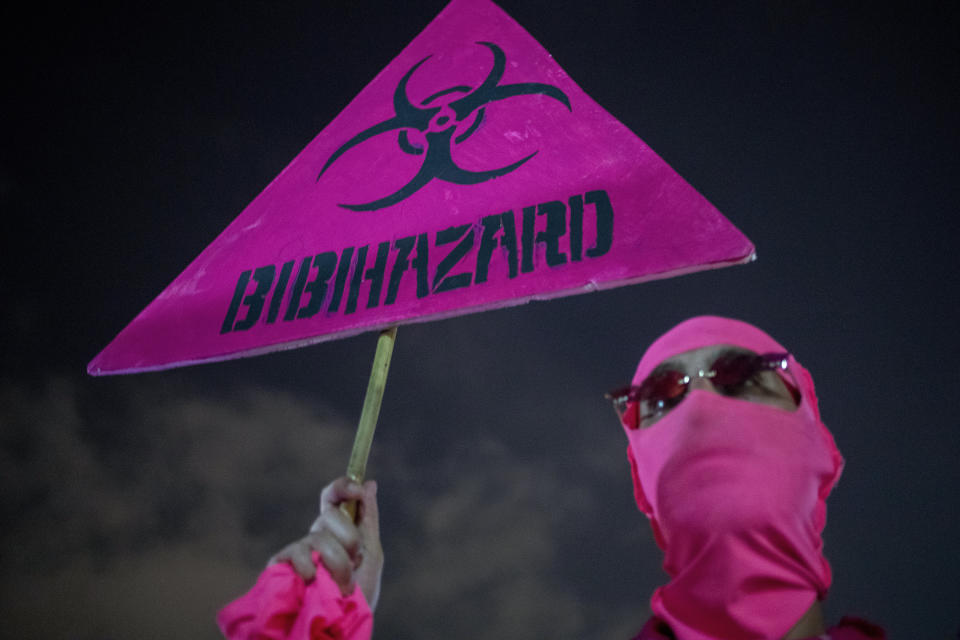 A protester holds a banner against Israeli Prime Minister Benjamin Netanyahu and the coronavirus countrywide lockdown in Tel Aviv, Israel, Thursday, Sept. 17, 2020. Netanyahu's government has imposed a three-week lockdown, beginning on Friday afternoon. (AP Photo/Ariel Schalit)