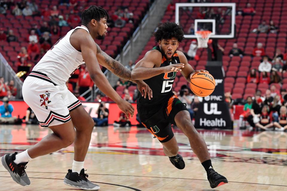 Miami forward Norchad Omier (15) drives past Louisville forward Sydney Curry (21) during the first half of an NCAA college basketball game in Louisville, Ky., Sunday, Dec. 4, 2022. (AP Photo/Timothy D. Easley)