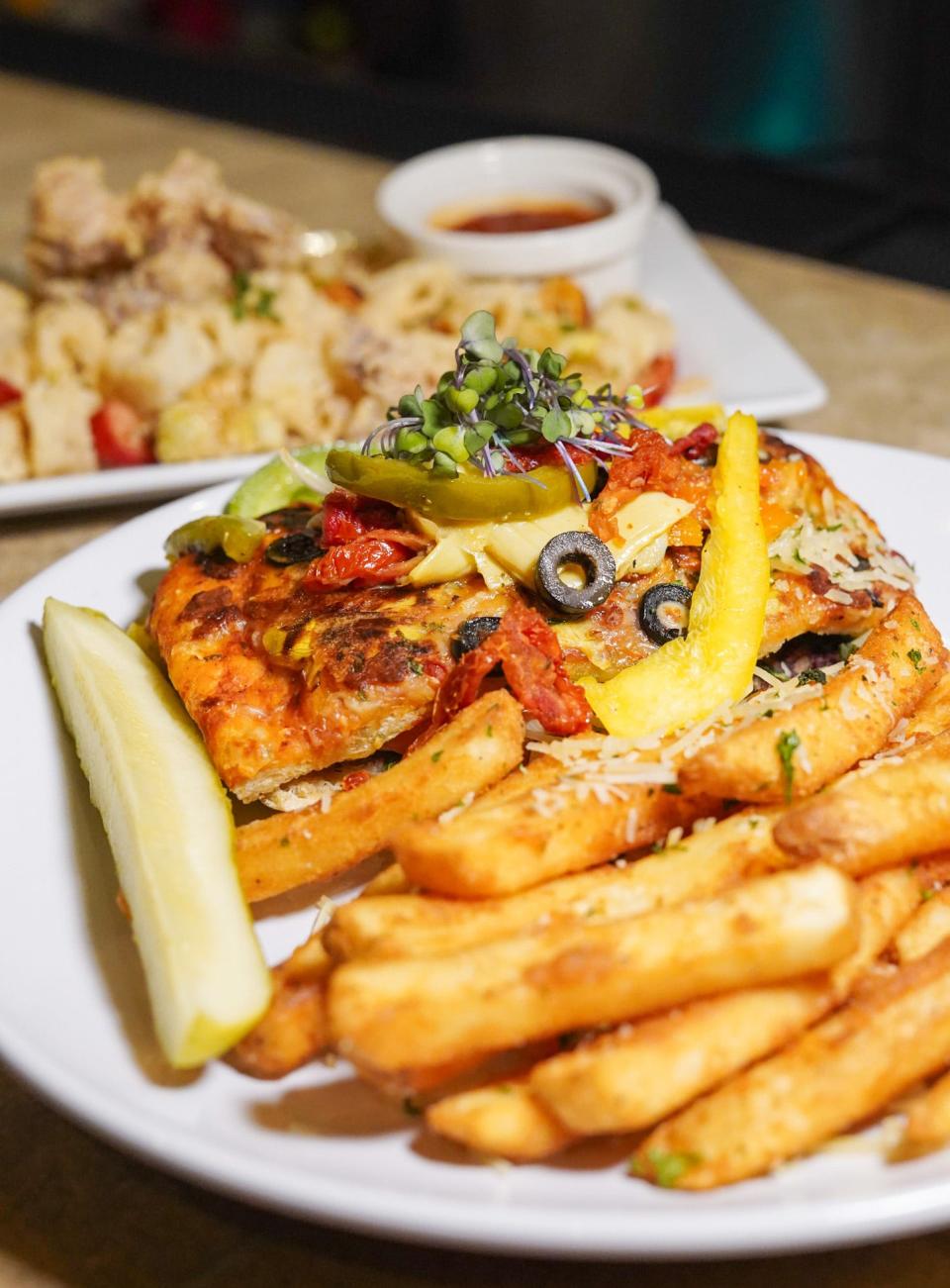 The vegetable panini, served with truffle parm fries, will be on the menu at the new Che Bello next month. A calamari appetizer can be seen in the background.